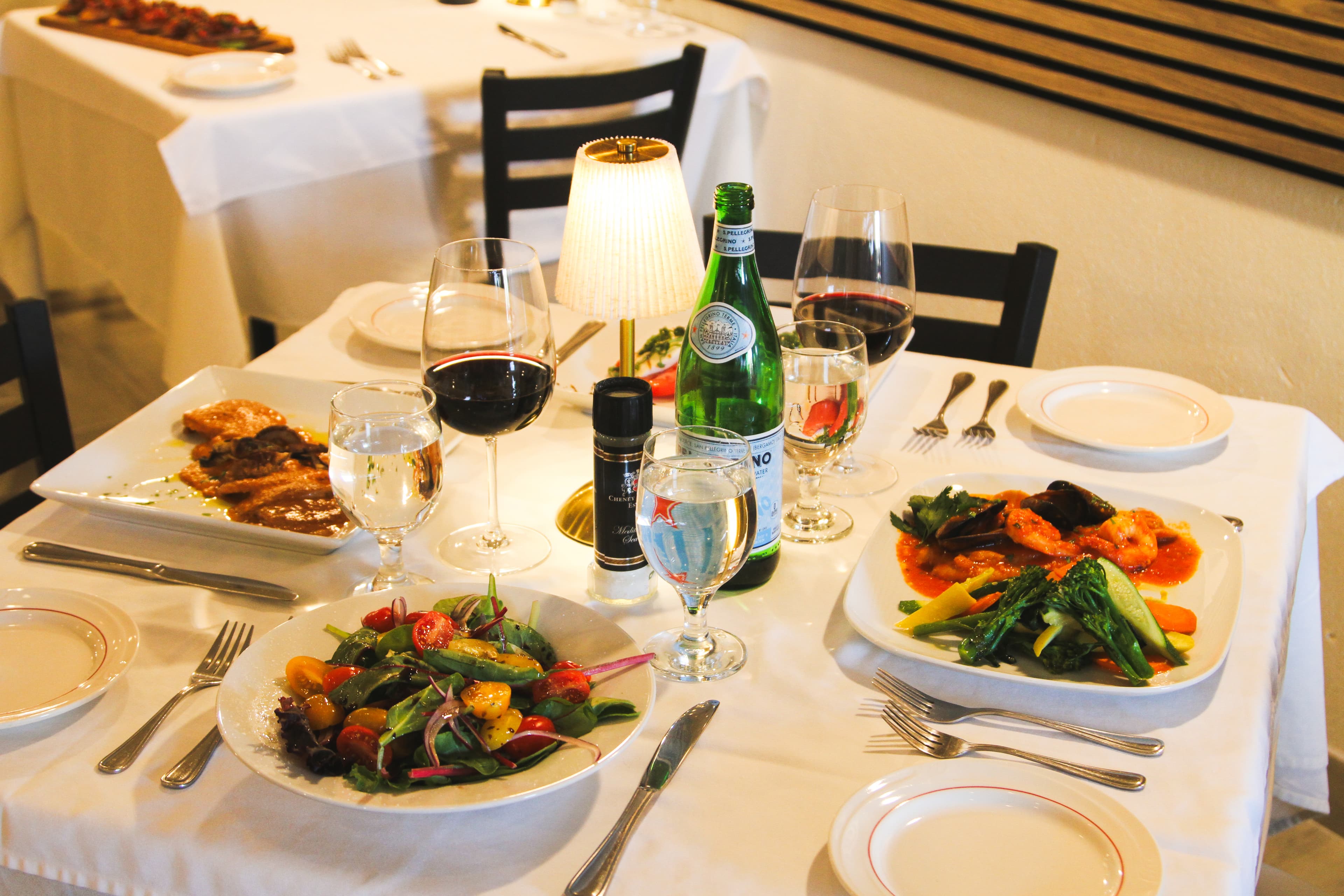 A full table at D'Corato Ristorante: wine, salad, and the night's dinners